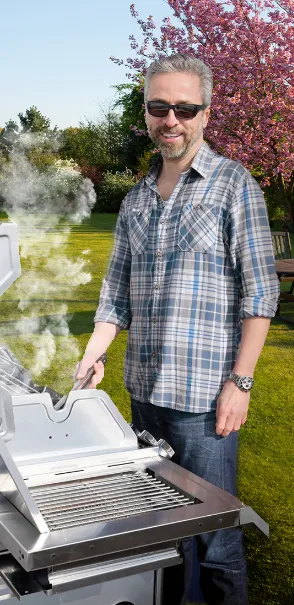 Smiling man engaged in grilling, showcasing the joy of outdoor cooking.