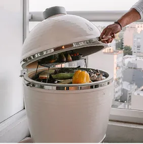 Cremeweißer Kamado B10 mit Grillgemüse auf einem Stadtbalkon