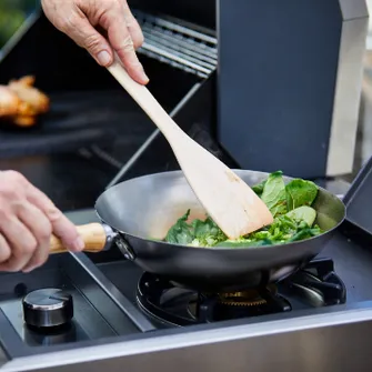 Grünes Gemüse, dass in einer Grillpfanne auf dem Kochfeld eines Grills zubereit wird