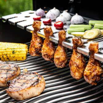 Großaufnahme eines Grillrosts der reichlich mit Fleisch und Gemüse belegt ist