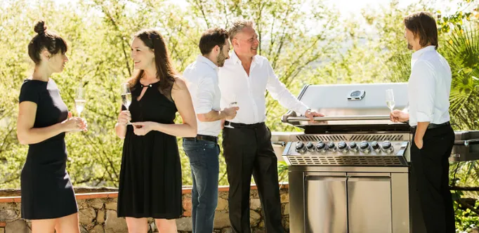 Gruppe von fünf elegant angezogenen Menschen die Grillen und sich dabei unterhalten