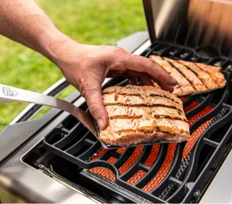A roasted steak being flipped on the grill grate