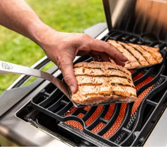 Ein gebratenes Steak, das gerade auf dem Grillrost gewendet wird