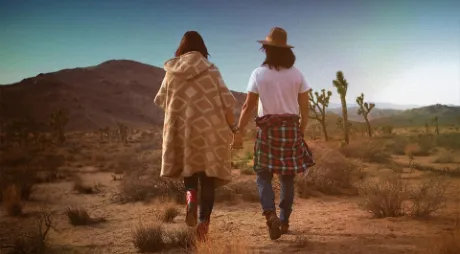 Couple walking hand in hand through a prairie